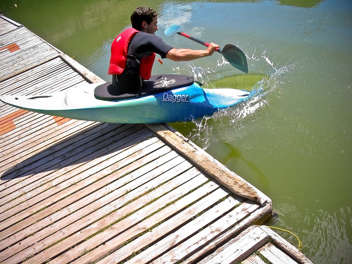 A kayaker pushing off from a sandy shore