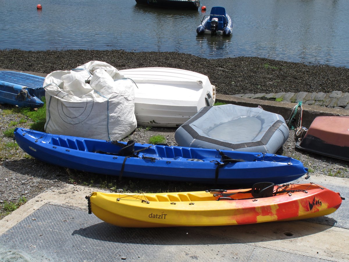 A sit-on-top and a sit-inside kayak side by side on a shore